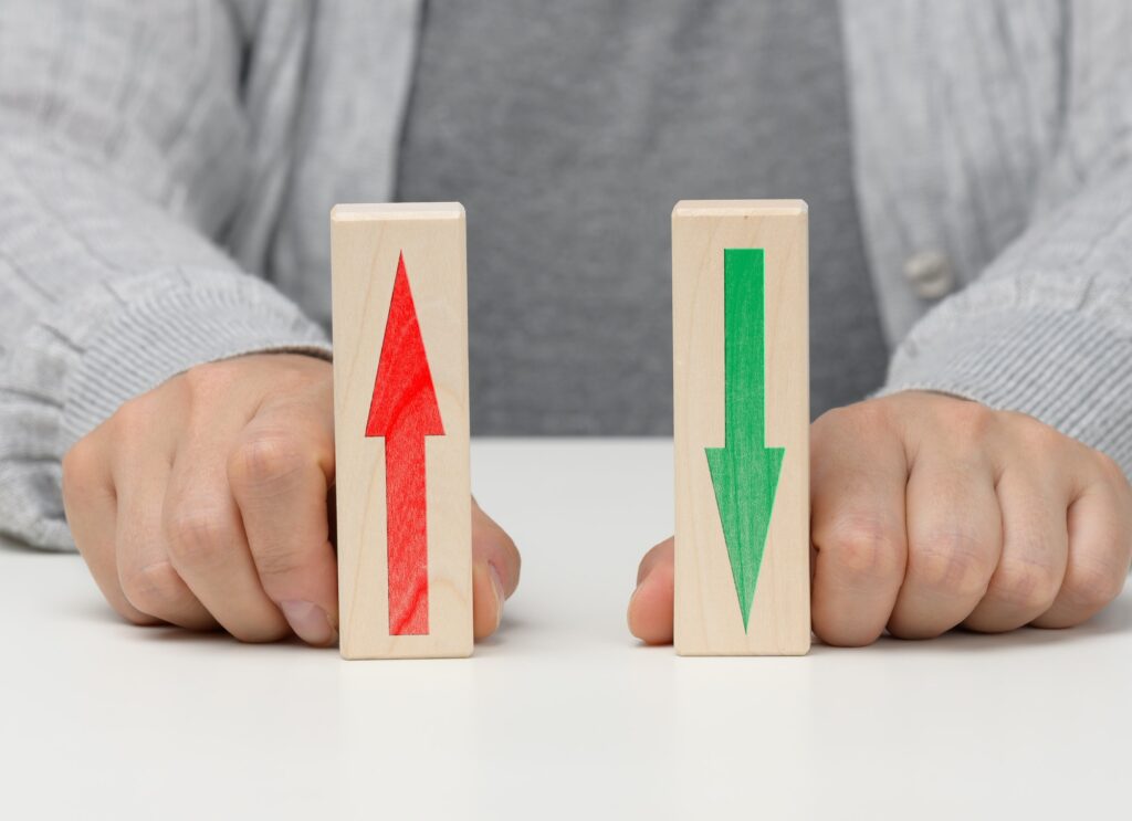 Female hand holds wooden blocks with up and down arrows.