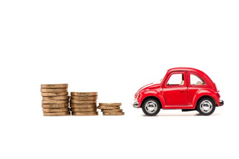 red toy car and golden coins on white