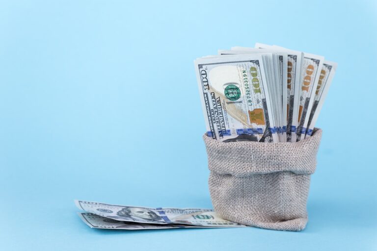 One hundred dollar bills in a linen bag on a blue background with free space for text