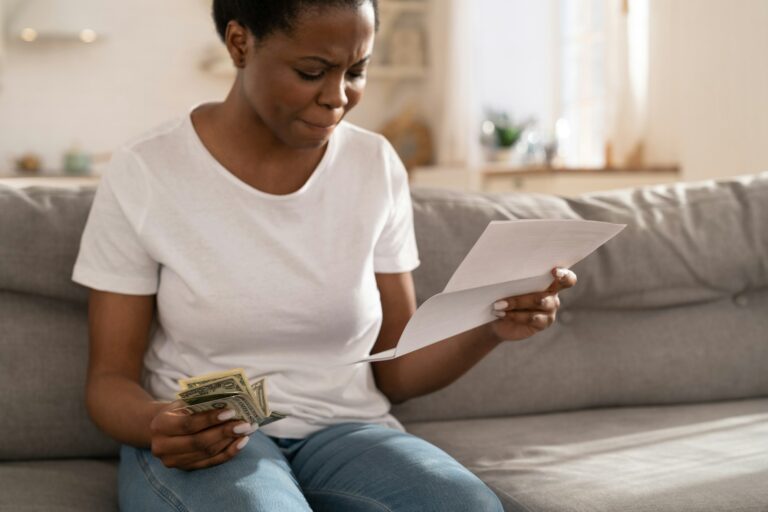 African woman frustrated about lack of finances, feeling anxiety about overdue mortgage payment.