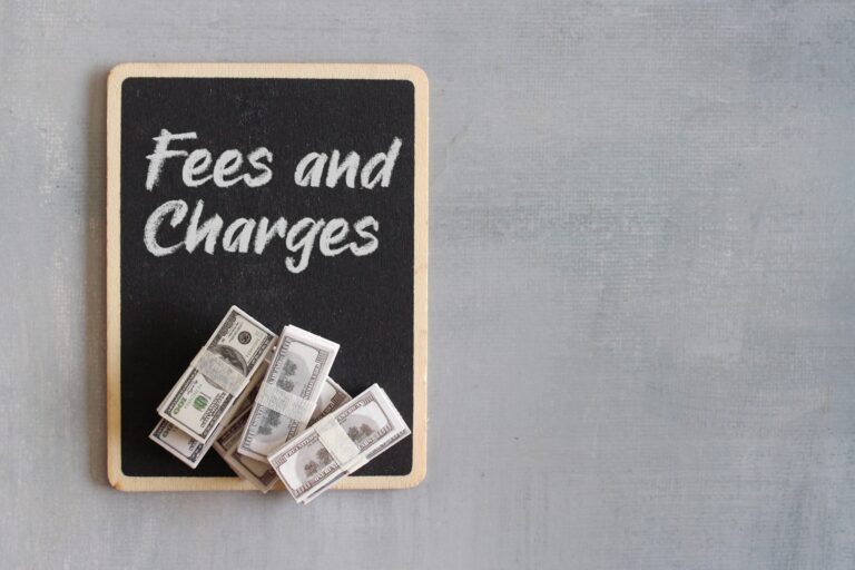 Top view image of money and chalkboard with text FEES AND CHARGES.